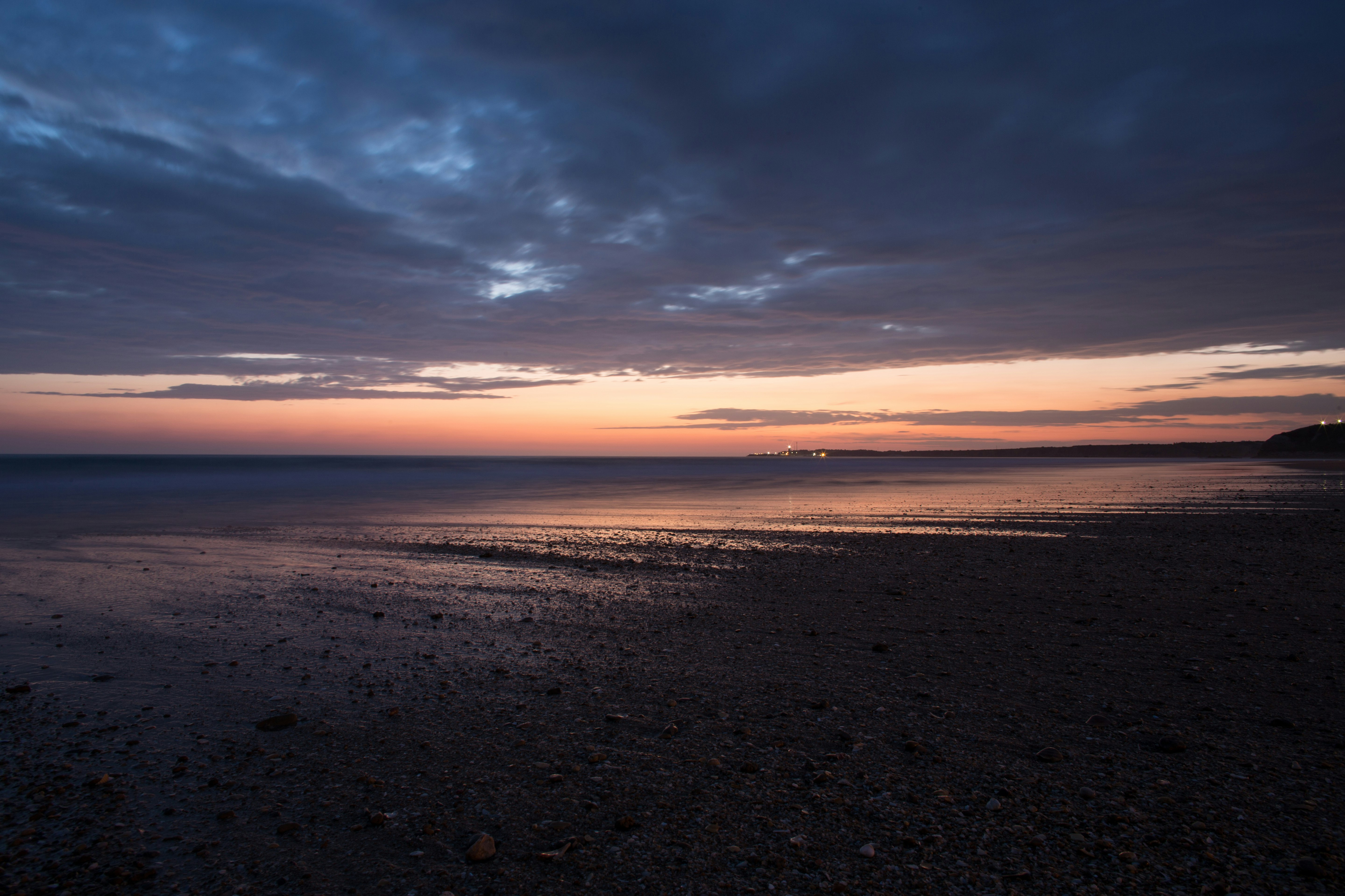 sea waves crashing on shore during sunset